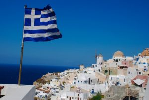 Řecká vlajka na letním ostrově a bílé domy pod ní 